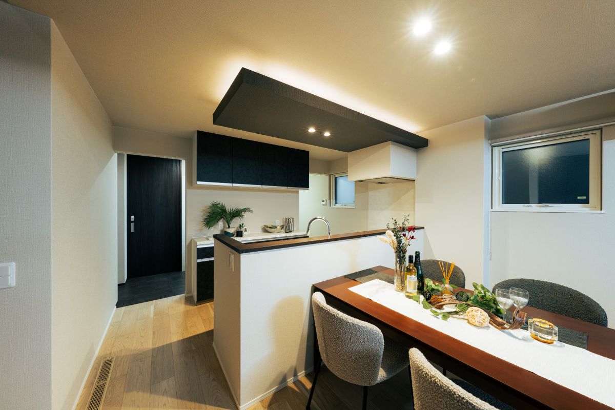 モダンなカウンターキッチンと、食事がセットされた木製ダイニングテーブルがある、明るいダイニングルーム。