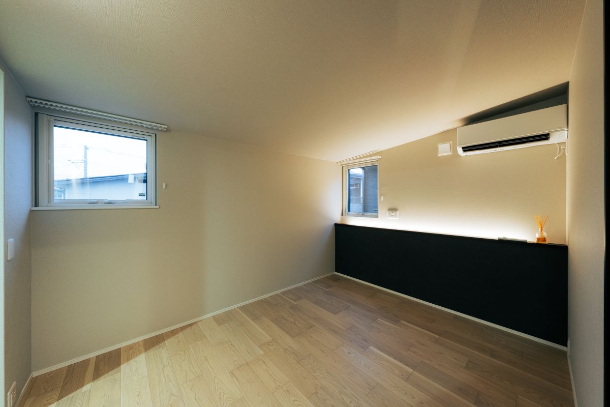 明るい木製フローリングと間接照明付きの腰壁がある、シンプルでナチュラルな洋室。