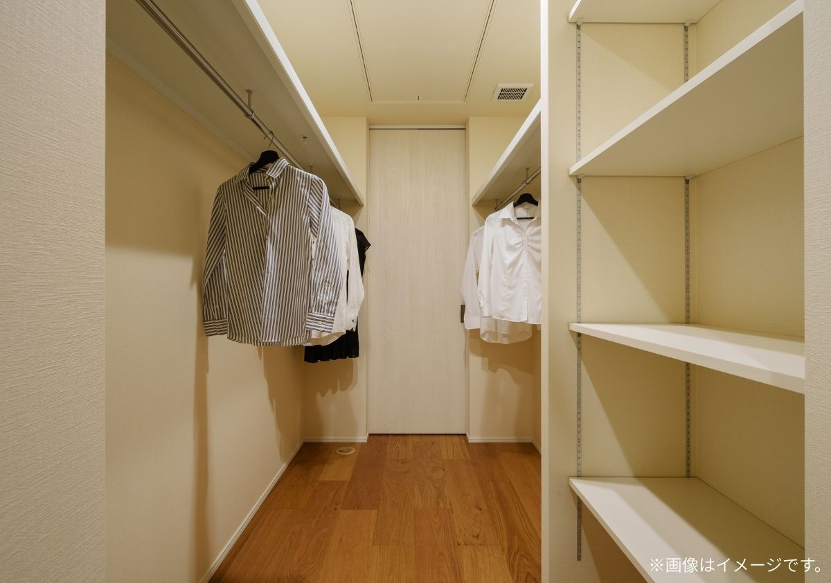 寝室から洗面室へ繋がるウォークスルークローゼット。両サイドにハンガーパイプと可動棚を備えた機能的な収納。